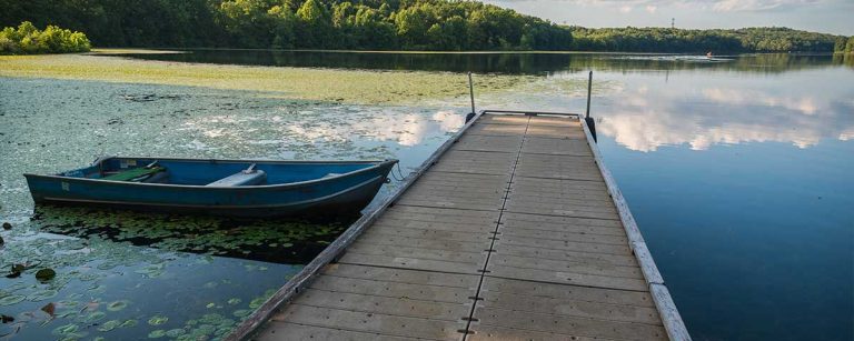 Small fishing boat near a wooden dock on a quiet Pennsylvania lake, perfect beginner-friendly fishing spot